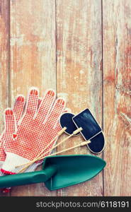 gardening and planting concept - close up of trowel, nameplates and garden gloves on table
