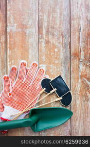 gardening and planting concept - close up of trowel, nameplates and garden gloves on table