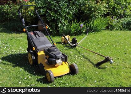 Gardening equipment, mower and brush cutter in a garden during spring. Gardening equipment, mower and brush cutter