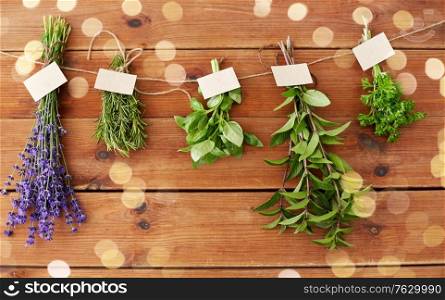 gardening, ethnoscience and organic concept - bunches of greens, spices or medicinal herbs with name tags on wooden background. greens, spices or medicinal herbs on wood