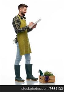 gardening, farming and people concept - happy smiling male gardener or farmer in apron and rubber boots with clipboard and box of garden tools over white background. happy gardener with clipboard with garden tools