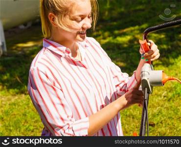 Gardening. Female person being mowing green lawn with lawnmower, in sunny day.. Woman being mowing lawn with lawnmower