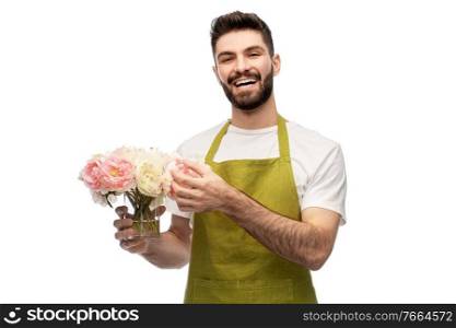 gardening, floristry and people concept - happy smiling male gardener in apron with bunch of peony flowers over white background. smiling male gardener with bunch of peony flowers