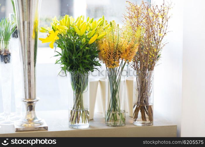 gardening, floristry, sale, holidays and flora concept - close up of flowers in vases at flower shop window