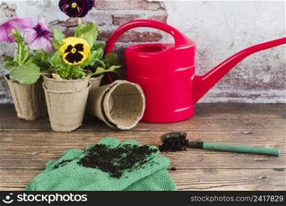 gardening flowers peat pots watering can shovel gardening gloves wooden desk