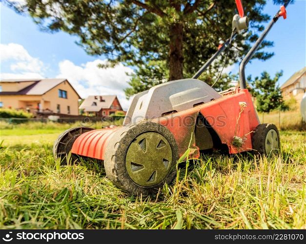Gardening, garden service. Old lawn mower cutting green grass in backyard. Mowing field with lawnmower in sunny day.. Old lawn mower