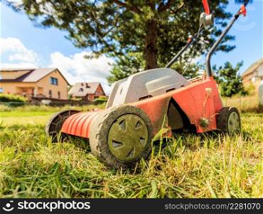 Gardening, garden service. Old lawn mower cutting green grass in backyard. Mowing field with lawnmower in sunny day.. Old lawn mower