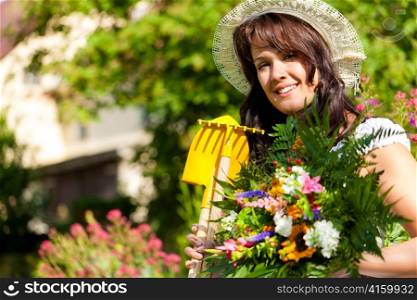 Gardening in summer - happy woman with flowers and hat in her garden