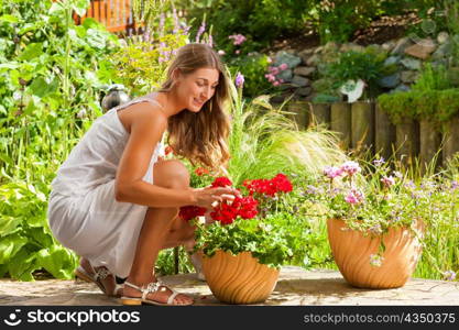 Gardening in summer - happy woman with flowers her garden