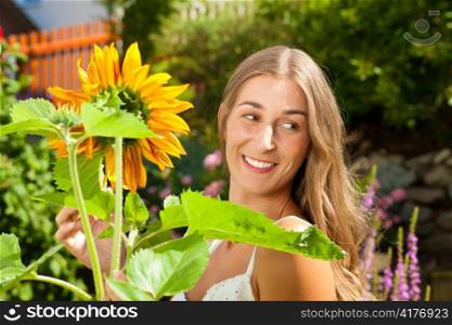 Gardening in summer - happy woman with sun flowers in her garden