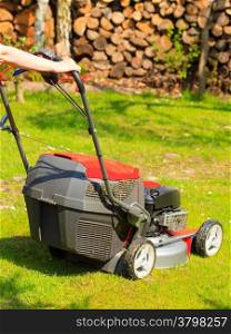 Gardening. Mowing green lawn with red lawnmower in spring day.