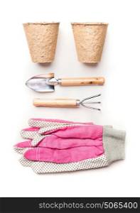 Gardening or planting concept with garden tools, planting peat pots and pink gloves on white background, top view, flat lay