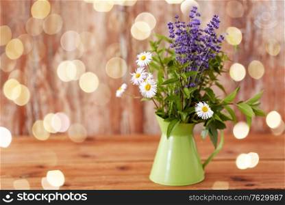 gardening, plants and organic concept - bunch of herbs and flowers in green jug on table. bunch of herbs and flowers in green jug on table