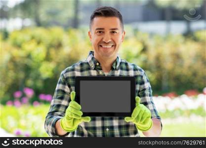 gardening, technology and people concept - happy smiling middle-aged man showing tablet pc computer at summer garden. happy man with tablet pc at summer garden