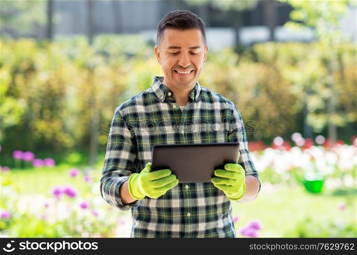 gardening, technology and people concept - happy smiling middle-aged man with tablet pc computer at summer garden. happy man with tablet pc at summer garden