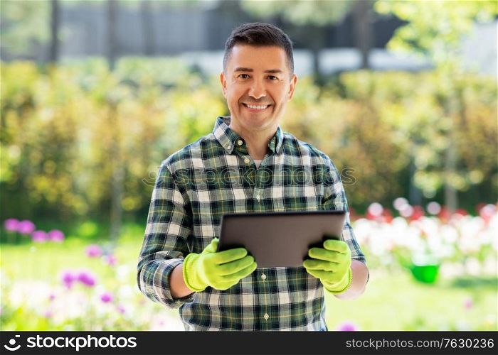 gardening, technology and people concept - happy smiling middle-aged man with tablet pc computer at summer garden. happy man with tablet pc at summer garden