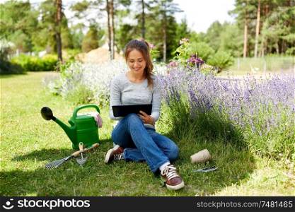 gardening, technology and people concept - happy young woman or gardener with tablet computer and garden tools in summer. woman with tablet pc and garden tools in summer