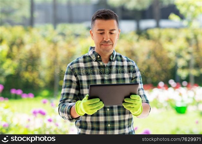 gardening, technology and people concept - middle-aged man with tablet pc computer at summer garden. man with tablet pc at summer garden