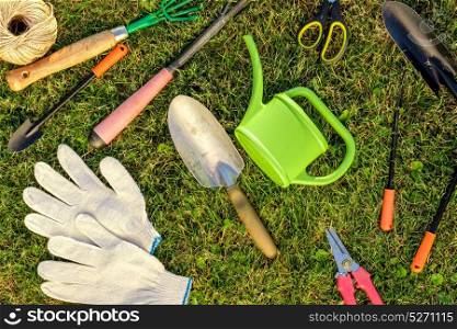 Gardening tools and watering can on grass top view