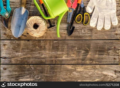 Gardening tools and watering can on wooden background with copy space for text top view
