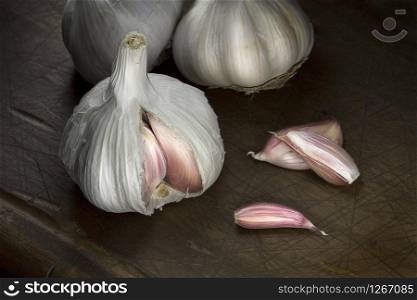 Garlic and garlic cloves on cutting board. Low key photography Close up