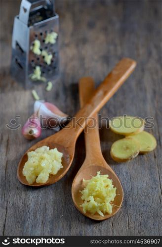 garlic and ginger in wooden spoons on wooden table