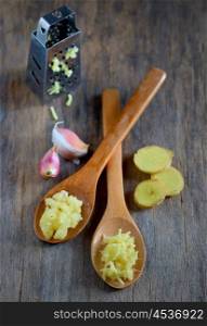 garlic and ginger in wooden spoons on wooden table