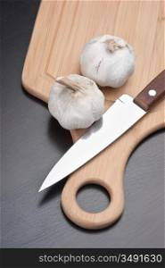 garlic and knife on a kitchen cutting board