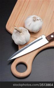 garlic and knife on a kitchen cutting board