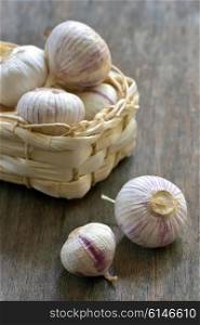garlic and small basket on wood background