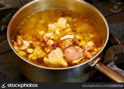 Garlic boiling soup in a pan at kitchen fire