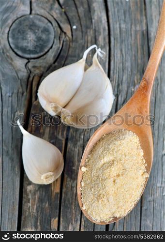 garlic cloves, bulb and powder on old wooden plates