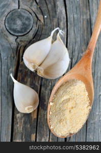 garlic cloves, bulb and powder on old wooden plates