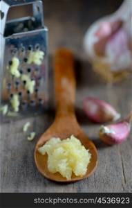 Garlic in spoon on wooden background