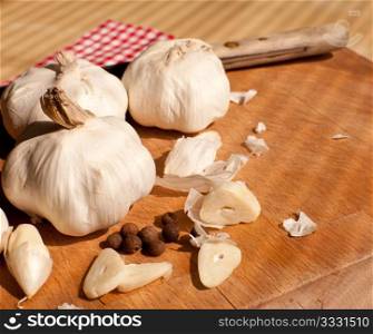 Garlic, kitchen knife and allspice on chopping board