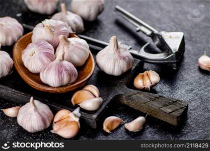 Garlic on a wooden plate on a cutting board. On a black background. High quality photo. Garlic on a wooden plate on a cutting board.