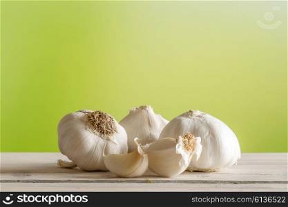 Garlic on a wooden table on green background