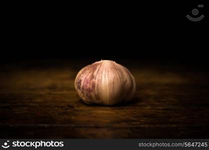 Garlic on wooden surface and black background