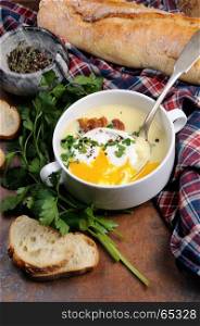 Garlic potato cream soup with bacon and poached eggs, herbs, spices