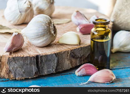 Garlic with essential oil in a bottle near ripe garlic on a background of old blue boards. Cure or seasoning with garlic.. Garlic with essential oil in a bottle near ripe garlic on a background of old blue boards.