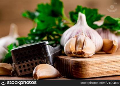 Garlic with parsley on a wooden cutting board. On a wooden background. High quality photo. Garlic with parsley on a wooden cutting board.