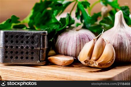 Garlic with parsley on a wooden cutting board. On a wooden background. High quality photo. Garlic with parsley on a wooden cutting board.