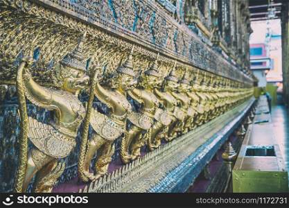 Garuda Wat Phra Kaew in Bangkok, Thailand - A line of ornate golden demons at the Grand Palace.