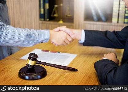 Gavel Justice hammer on wooden table with judge and client shaking hands after adviced in background at courtroom, lawyer service concept 