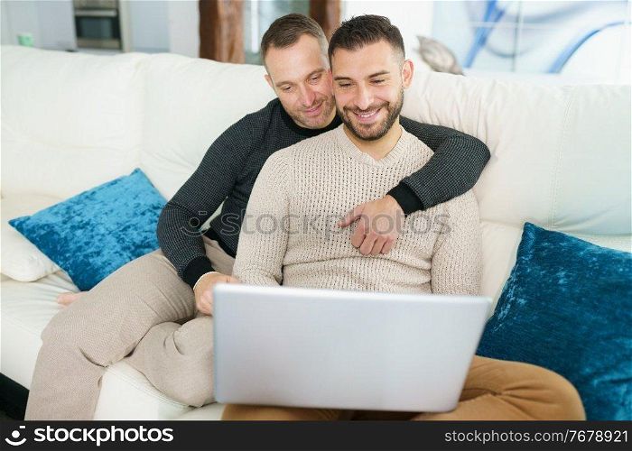 Gay couple consulting their travel plans together with a laptop. Homosexual Lifestyle concept.. Gay couple consulting their travel plans together with a laptop.