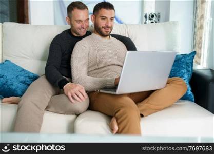 Gay couple consulting their travel plans together with a laptop. Homosexual Lifestyle concept.. Gay couple consulting their travel plans together with a laptop.
