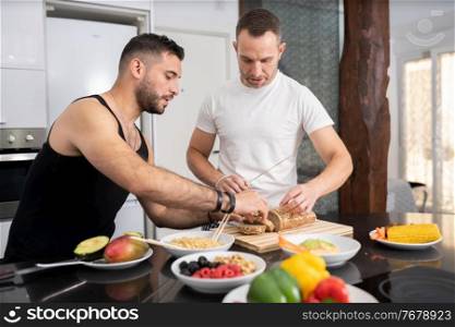 Gay couple cooking healthy vegan food together at home. Homosexual relationship concept.. Gay couple cooking healthy vegan food together at home.