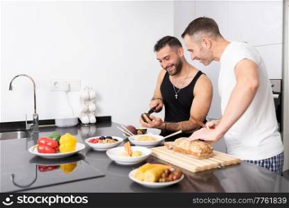 Gay couple cooking healthy vegan food together at home. Homosexual relationship concept.. Gay couple cooking healthy vegan food together at home.