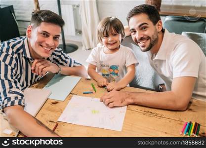 Gay couple having fun with their son while drawing together at home. Family concept.
