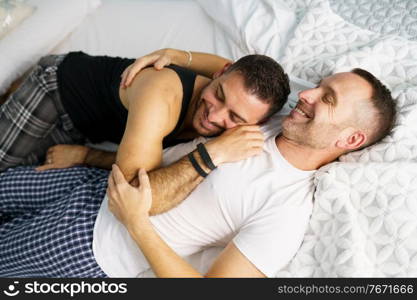 Gay couple hugging together on their bed. Homosexual lifestyle concept.. Gay couple hugging together on their bed.